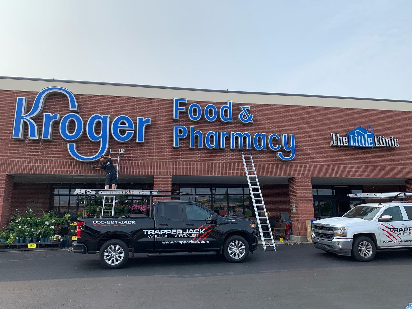 A Kroger Food & Pharmacy storefront with service vehicles parked outside.