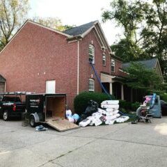 Brick house with insulation installation equipment outside.