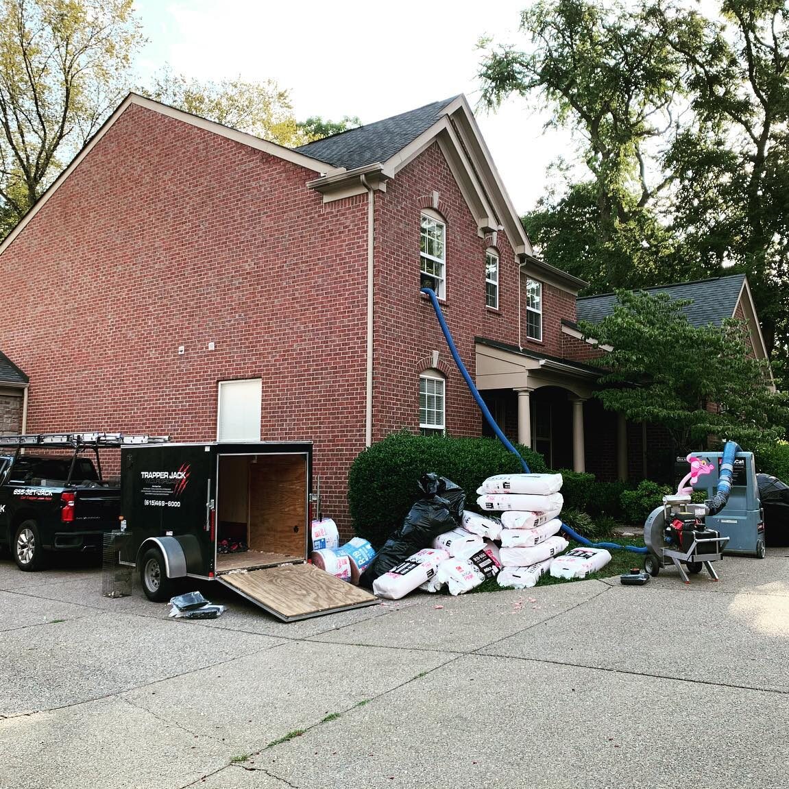 House with landscaping supplies and equipment outside.