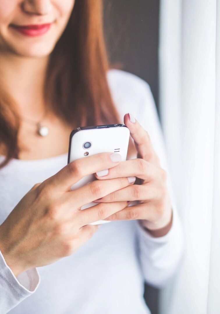 Woman smiling while using a smartphone.